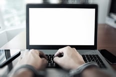 Businessman hand in handcuffs at wooden desk with laptop computer and digital tablet and stylus pen and smart phone as Cyber-Crime concept-1