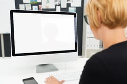 Over the shoulder view of a businesswoman working at a blank computer monitor with a white screen and copyspace